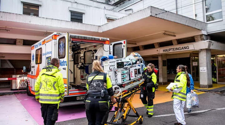 Rettungssanitäter und medizinische Fachpersonen schieben ein Baby auf einer Transportliege in einen Rettungswagen