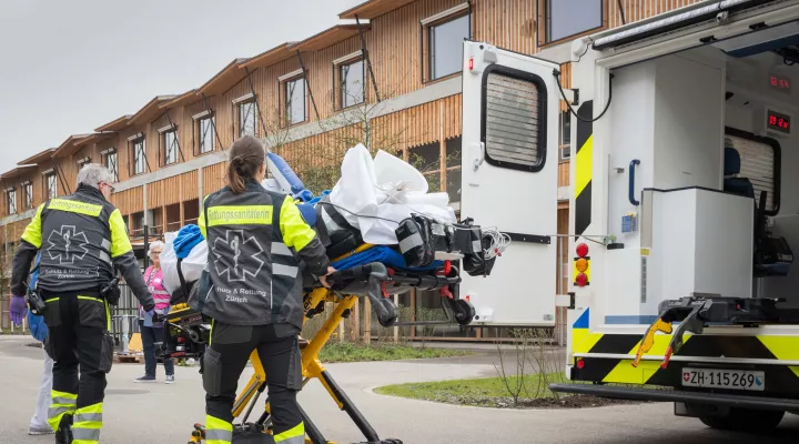 Rettungssanitäterinnen transportieren ein Kind auf einer Liege aus der Ambulanz ins Kinderspital