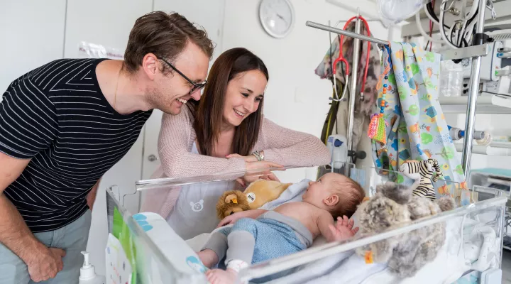 Junge Eltern lachen ihren Sohn an im Kinderspital Zürich