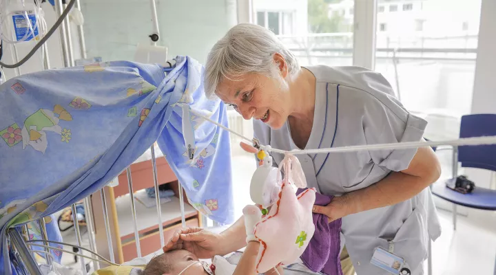 Eine freiwillige Helferin spielt mit einem Baby auf der Neonatologie