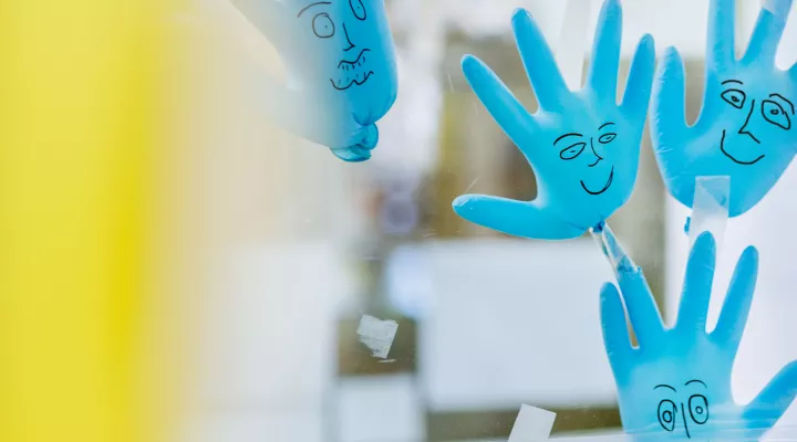 Blaue Plastikhandschuhe mit aufgemalten Gesichtern kleben an der Scheibe der Kabine, Stammzellentransplantation