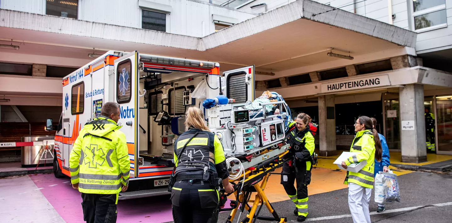 Rettungssanitäter und medizinische Fachpersonen schieben ein Baby auf einer Transportliege in einen Rettungswagen