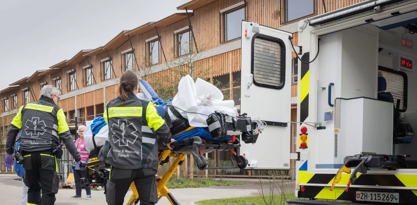 Rettungssanitäterinnen transportieren ein Kind auf einer Liege aus der Ambulanz ins Kinderspital