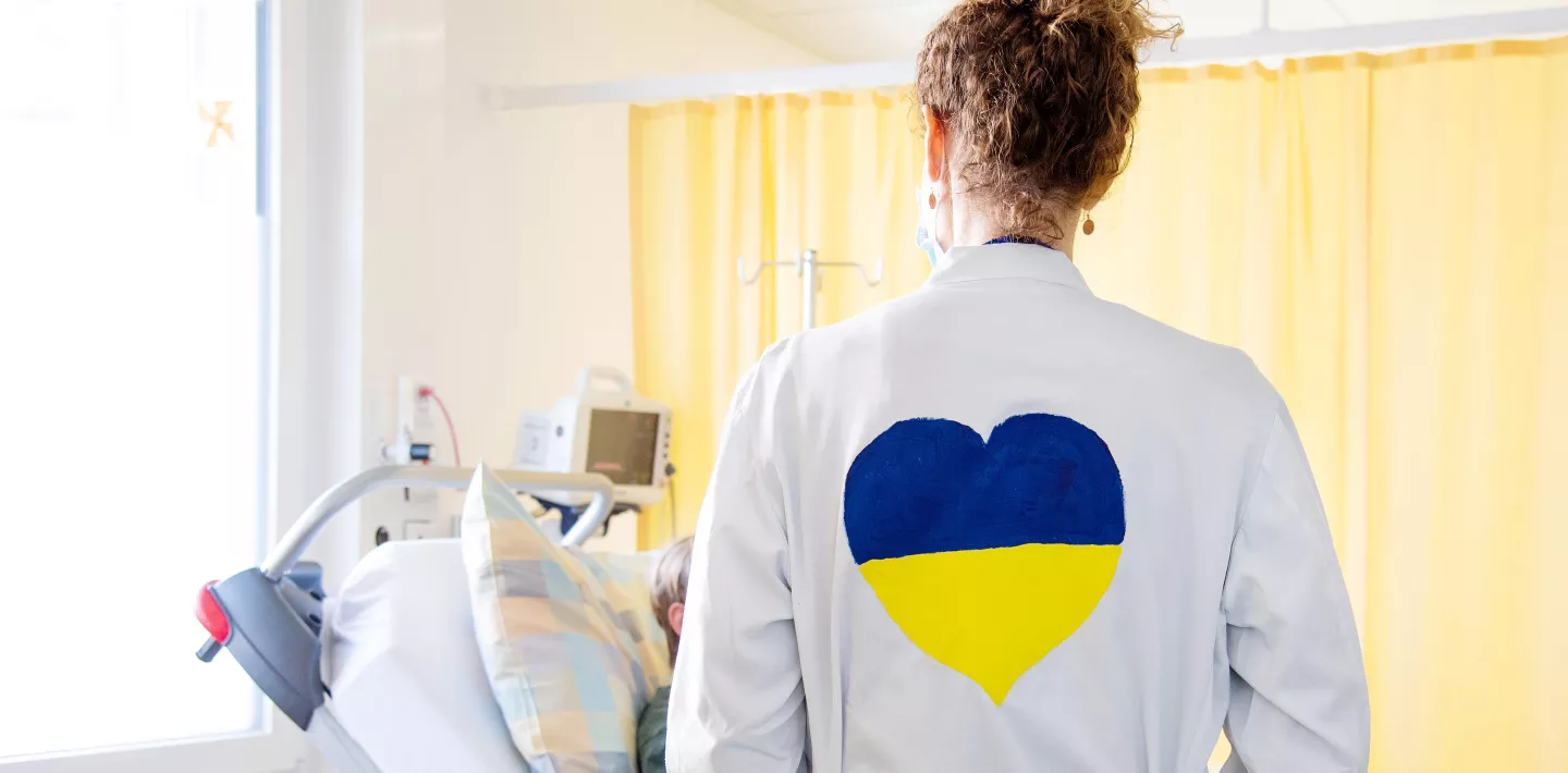 Ärztin mit Ukraine-Farben am Patientenbett