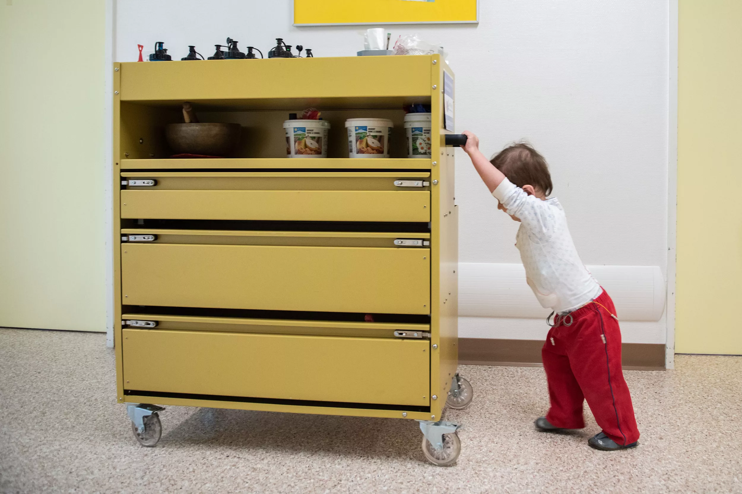 Ein Kind schiebt einen Wagen mit Kunstbedarf auf dem Gang des Kinderspitals Zürich